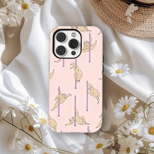 May include: A phone case with a repeating pattern of sloths pole dancing on a light pink background. The sloths are tan with purple poles. The phone case has a black camera module.