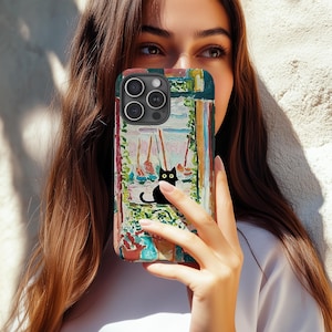 May include: A colorful phone case featuring an artistic painting of a black cat with yellow eyes, sitting in front of a window. The case has a vibrant, multi-colored design with green, blue, and red hues.