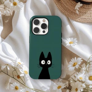 Puede incluir: Funda de teléfono verde oscuro con una ilustración de gato negro. El gato tiene ojos blancos grandes y redondos y un diseño minimalista. La funda tiene un acabado brillante y un recorte para la cámara.