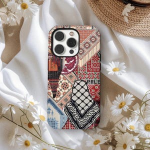 May include: A patterned phone case featuring a patchwork design with red, white, black, and blue geometric patterns. The case includes the word "PALE" and is surrounded by white daisies.