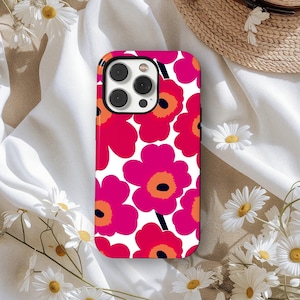 Puede incluir: Funda de teléfono con un llamativo diseño floral. El diseño presenta grandes flores estilizadas en tonos rosa, naranja y negro sobre un fondo blanco. La funda tiene un acabado brillante y un recorte para la cámara.