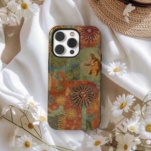 May include: A colorful phone case with a unique design featuring a sun, turtle, and other artistic elements. The case has a mix of orange, green, and brown tones, creating a vintage aesthetic. The case is designed to fit a smartphone.