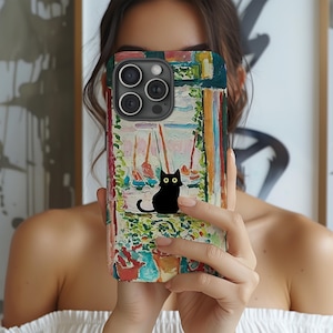 May include: A colorful phone case featuring a black cat with yellow eyes, set against a backdrop of a seaside scene with sailboats. The case has a textured, artistic design with a mix of colors, including green, blue, red, and white.
