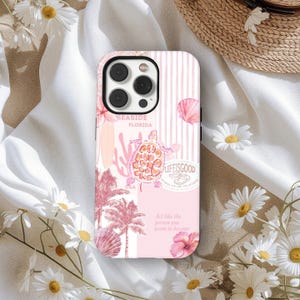 May include: A pink phone case with a beach theme. The case features a turtle, palm trees, and the words "Seaside Florida" and "Life is Good." The design includes pink stripes, flowers, and a seashell.