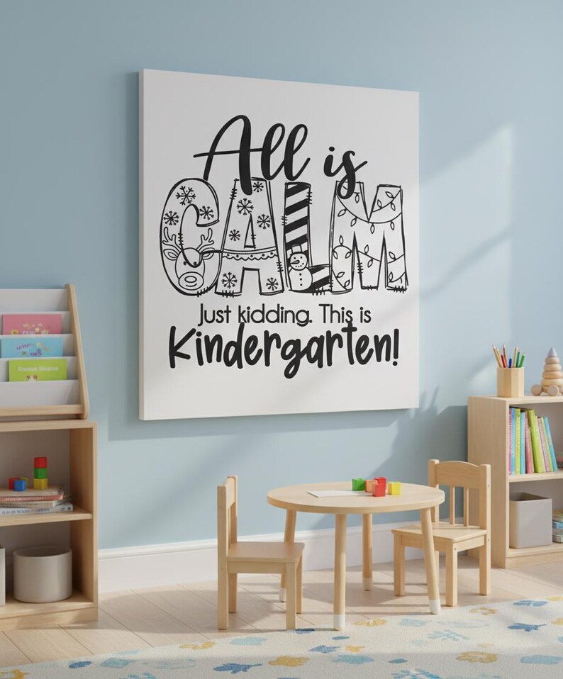 May include: A white canvas with the text "All is CALM Just kidding. This is Kindergarten!" in black. The word "CALM" is decorated with snowflakes, a reindeer, a snowman, and Christmas lights. A small wooden table and chairs are in front of the canvas.