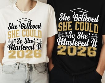 May include: White and black t-shirts with the text "She Believed SHE COULD So She Mastered It 2026" in gold and white. The shirts feature a graduation cap graphic, stars, and scrolls, celebrating the class of 2026.