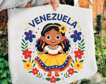 May include: White tote bag with a cartoon illustration of a girl in a yellow dress, encircled by flowers. The word "VENEZUELA" is arched above the girl's head in blue. The girl has dark hair and a flower in her hair.