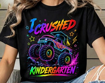 May include: Black t-shirt with a colorful graphic of a monster truck wearing a graduation cap. The text "I Crushed Kindergarten" is displayed in a rainbow gradient. The design includes stars and lightning bolts.