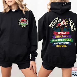 Op de afbeelding: Zwarte hoodie met een voorzak en een capuchon. De voorkant heeft een cirkelvormig ontwerp met de tekst: "WE GOT THE PEOPLE, UTLA, SEIU, TEAMSTERS, AALA, 2026." De achterkant toont "WE GOT THE PEOPLE, WE GOT THE POWER" en de tekst: "UTLA, SEIU, TEAMSTERS, UNION STRONG, 2026."