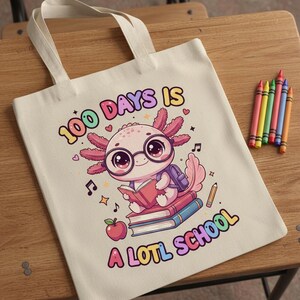 May include: A cream-colored tote bag with the text "100 DAYS IS A LOTL SCHOOL" and a cartoon axolotl wearing glasses and a backpack, reading a book. Colorful crayons are to the right.