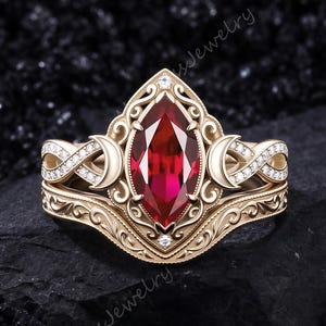 Peut inclure: Une bague en or avec une pierre rouge centrale taille marquise entourée de volutes complexes et de motifs en croissant de lune. L'anneau est orné de petites pierres blanches et comprend une alliance assortie aux détails gravés.