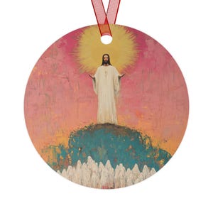 Op de afbeelding: Een ronde, kleurrijke ornament met een schilderij van een figuur in witte gewaden met uitgestrekte armen, staande op een heuveltop met een gouden halo. De figuur wordt omringd door een menigte mensen in witte gewaden.