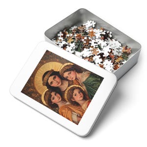 Può includere: Una scatola bianca per puzzle con coperchio aperto, che rivela un puzzle parzialmente assemblato. Il puzzle presenta un dipinto in stile rinascimentale di quattro donne con aureole. La scatola contiene pezzi di puzzle sciolti, pronti per l'assemblaggio.
