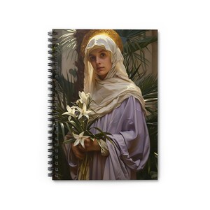 May include: Spiral-bound notebook featuring a classical painting of a woman in a white veil and purple robe, holding white lilies. The artwork has a golden halo and is set against a backdrop of lush green foliage. The notebook's spiral binding is black.
