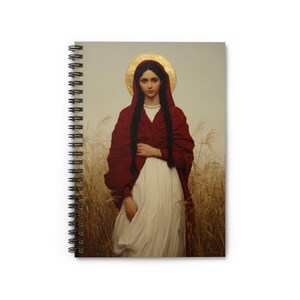 May include: A spiral-bound notebook featuring a cover illustration of a person with long dark braided hair, wearing a white dress and a deep red shawl. A golden circular halo is positioned behind the head, set against a field of wheat.
