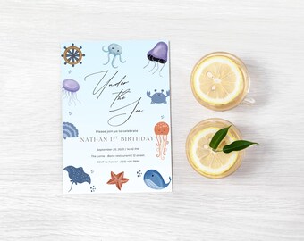 Puede incluir: Una invitación con el tema "Bajo el mar", con ilustraciones de criaturas marinas. La invitación incluye el texto "Nathan 1er cumpleaños" y los detalles del evento. También se ven dos vasos de limonada con rodajas de limón.