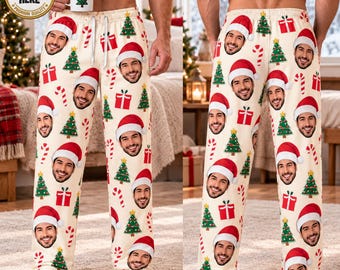 May include: Cream-colored pajama pants featuring an all-over print of a repeating man's face wearing a Santa hat, interspersed with green Christmas trees, red gift boxes, and red and white candy canes. The pants have a white drawstring waist.