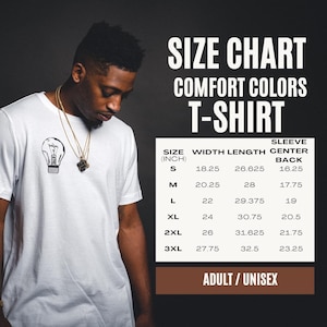 Pu&ograve; includere: Una t-shirt bianca con una piccola grafica di una lampadina nera sul petto. Accanto alla maglietta c'&egrave; una tabella delle taglie per le t-shirt Comfort Colors, che elenca le taglie dalla S alla 3XL con misure in pollici per larghezza e lunghezza.