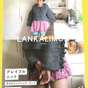 Op de afbeelding: Een vrouw draagt een grijze gehaakte trui met een grote kraag, een roze bloemenrok en een blauwe geruite short. De afbeelding komt uit een Japans knutselboek, met de tekst "LANKALIM", "DARUMA" en "#2".