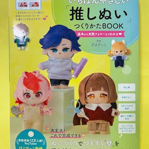 Könnte beinhalten: Ein japanisches Anleitungsbuch mit dem Titel 'Ichiban Yasashii Oshi Nui Tsukurikata BOOK' mit einem hellgrünen Einband, das vier kleine Plüschpuppen, Nähwerkzeuge und japanischen Text zur Anleitung der Puppenherstellung zeigt.