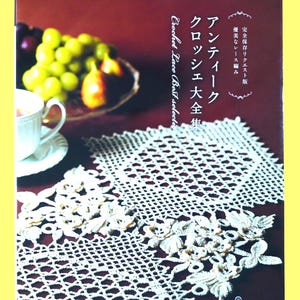 May include: A book cover with the text "applemints" and Japanese text. The book features a white crocheted lace doily with floral designs. A cup of tea and a bowl of fruit are in the background.