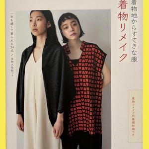 May include: A book cover with two women modelling clothing. One wears a black jacket over a cream dress, the other a black and red patterned top. Japanese text is visible on the cover.