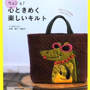 May include: A burgundy tote bag with a quilted pattern, featuring an appliqué of a green alligator wearing pink sunglasses and a necklace. The bag has black handles and Japanese text on the cover.