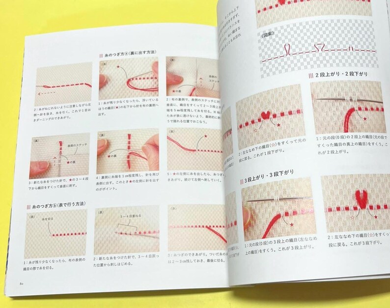 Puede incluir: Libro abierto con ilustraciones detalladas de t&eacute;cnicas de bordado. Las p&aacute;ginas muestran instrucciones paso a paso con hilo rojo sobre tela beige. Diagramas y texto japon&eacute;s acompa&ntilde;an las gu&iacute;as visuales, demostrando varios m&eacute;todos de puntada.