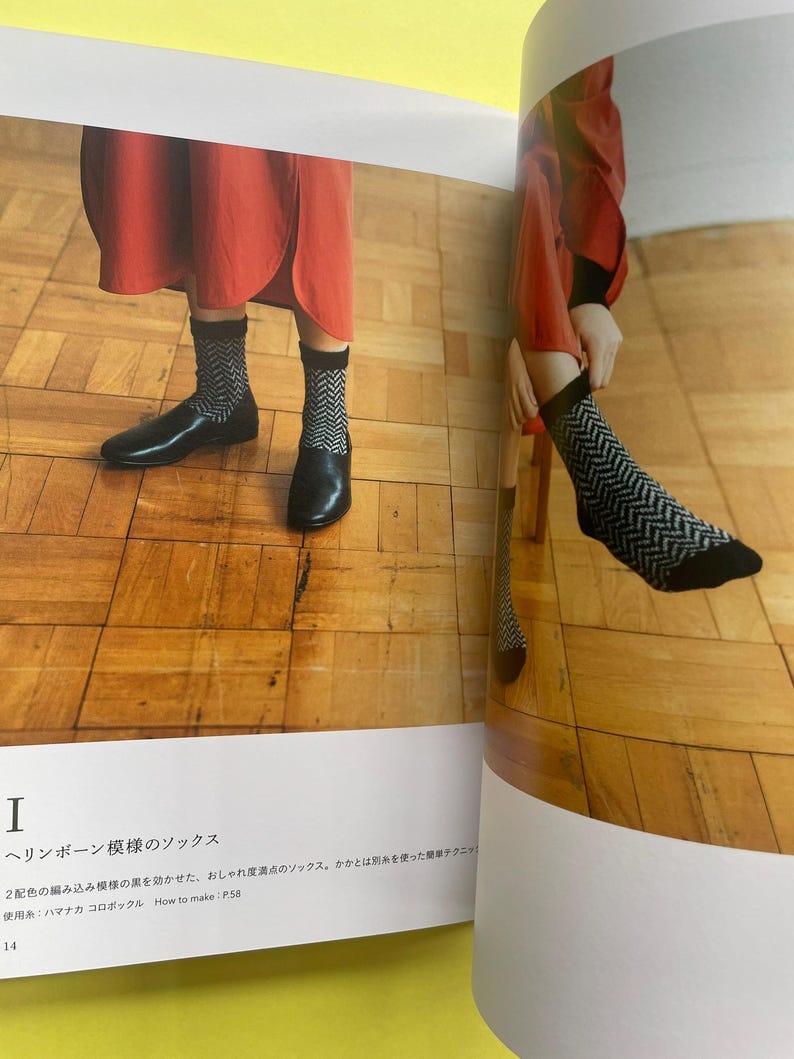 May include: A pair of black and white socks featuring a repeating herringbone pattern with solid black cuffs and toe sections. The socks are shown in a printed book layout alongside text that includes the Japanese title and How to make: P.58.