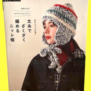 以下が含まれることがあります： 手作りのニット帽をかぶった女性が写っている本の表紙。帽子は白、黒、赤、ティール色。本のタイトルは日本語で、上部に「applemints」という言葉があります。