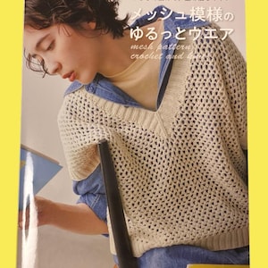 May include: A book cover featuring a person wearing a cream-colored, open-weave crochet sweater over a denim shirt. The book title includes Japanese text and the English phrase "mesh pattern crochet and knit". The book has a yellow border.