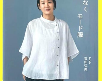Può includere: Copertina di un libro con una donna che indossa una camicetta bianca e pantaloni neri. Il testo giapponese recita "Mode Clothes". Il libro fa parte della "Heart Warming Life Series" e include modelli per le taglie S, M, L e LL.