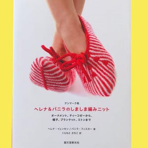 以下が含まれることがあります： 赤と白のストライプのニットスリッパが特徴の書籍の表紙。 書籍のタイトルと追加テキストは日本語です。 背景は薄い黄色です。