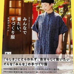 以下が含まれることがあります： 黒い水玉模様の紺色のシャツを着た女性が、日本語のテキストが書かれた本の表紙の前に立っています。本の表紙には「みんなで手作り服」というタイトルが表示されています。