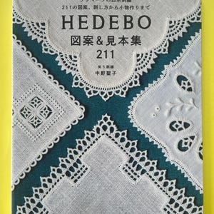 May include: A softcover book titled HEDEBO with white lace embroidery patterns on a dark teal background. The cover features intricate needlework designs, the number 211, and Japanese text including the author's name, Nakano Seiko, and book details.