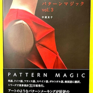 以下が含まれることがあります： 「パターンマジック vol. 3」の表紙。赤い衣服がマネキンにかけられています。表紙には日本語と英語のテキストがあり、タイトルと著者の名前が含まれています。本のテーマはパターンメイキングです。