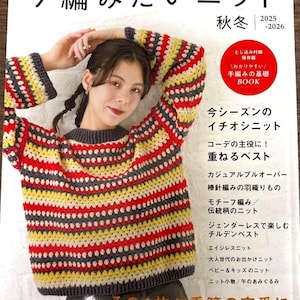 May include: A woman wearing a colorful, striped crochet sweater, with red, yellow, gray, and white horizontal stripes. The sweater is featured on the cover of a Japanese knitting book titled "I Want to Knit Now".