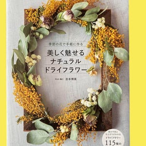 Op de afbeelding: Boekomslag met een krans van gedroogde bloemen in een houten frame. De krans bestaat uit gele, groene en witte bloemen. Japanse tekst is zichtbaar, inclusief de titel "Beautifully Charming Natural Dry Flowers."