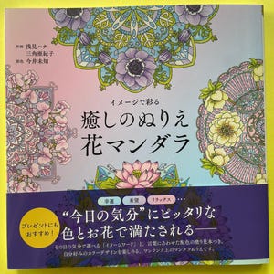 May include: A square coloring book with a pastel gradient background featuring intricate floral mandala illustrations in shades of purple, pink, and green. The cover displays Japanese text including the title and author credits, with a dark purple banner at the bottom containing additional Japanese text and circular icons.