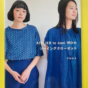 Op de afbeelding: Een softcover boek getiteld ATELIER to nani IRO no sewing closet met op de omslag een afbeelding van twee personen in blauwe kleding. De een draagt een blauwe top met witte stippen, de ander een effen blauwe tuniek met een knoopsluiting.
