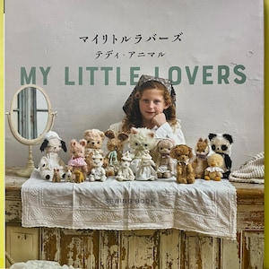 以下が含まれることがあります： 「My Little Lovers」というタイトルの裁縫本。表紙には、白いレースの布の上に並べられた小さな手作りのぬいぐるみと、その背後にいる人物が写っています。表紙には「applemints」、「My Little Lovers」、「SEWING BOOK」という文字が記載されています。