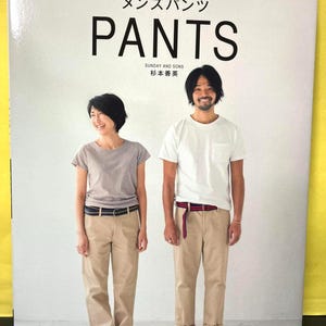 以下が含まれることがあります： 「PANTS」の文字が大きく書かれた本の表紙。日本語のテキストと、カーキ色のパンツとTシャツを着た2人の写真が掲載されています。サンデーアンドサンズ発行。
