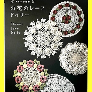 May include: A book cover featuring several white crochet doilies with floral designs. The cover has Japanese text and the English words "Flower Lace Doily." The doilies vary in size and include rose and other flower motifs. The book is set against a black background.