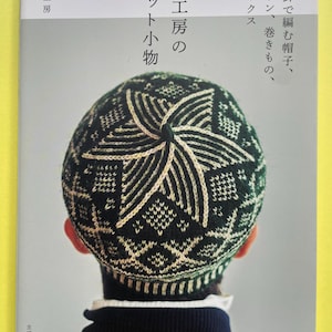 May include: A softcover book titled "風工房のニット小物" featuring a dark green and cream-coloured knit hat with a star-like geometric pattern on the cover. The book includes Japanese text and displays a person wearing the hat from a back view.
