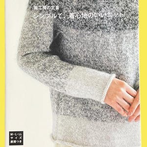May include: A book cover featuring a knitted sweater in shades of gray. The sweater has a striped design with a light gray bottom, a medium gray center, and a dark gray top. Japanese text is visible on the cover, along with the size information.