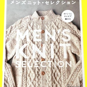 以下が含まれることがあります： ベージュ色のケーブル編みカーディガンと木製ボタンが特徴の書籍の表紙。タイトル「MEN'S KNIT SELECTION」が白いブロック体で表示されています。上部と下部に日本語のテキストがあり、サイズも示されています。