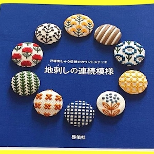 May include: A blue book with Japanese text and a collection of ten embroidered circular designs. The designs feature various patterns in red, white, yellow, brown, and green. The book is on a yellow background.