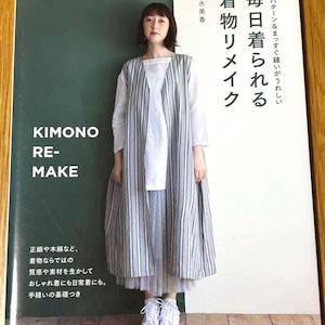 Könnte beinhalten: Buchcover mit japanischem Text und einer Frau in einem gestreiften Kimono-Kleidungsstück. Das Buch trägt den Titel "Kimono Re-Make". Die Frau trägt ein weißes Oberteil und einen Rock mit weißen Turnschuhen. Das Buch liegt auf einer Holzoberfläche.