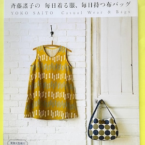 May include: A book cover titled Yoko Saito Casual Wear & Bags featuring a mustard yellow sleeveless top with a light blue abstract pattern and a hobo-style bag with a dark blue and olive green polka dot print against a white brick wall.