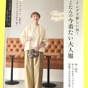 May include: A sewing pattern book cover featuring a person wearing a cream-coloured long-sleeve blouse and tan wide-leg trousers. The cover includes Japanese text, a floral patterned clutch, and mentions sizes S, M, L, and LL for the included patterns.